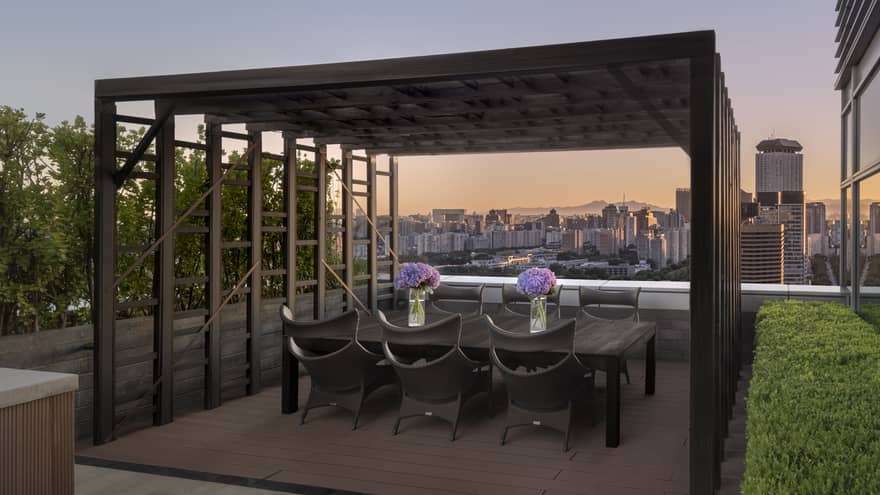Outdoor city rooftop terrace, with dining table under a pergola