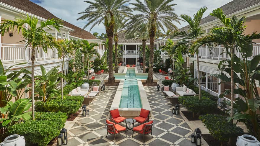Patio chairs, tables around cross-shaped fountain, large palm trees in Hartford Courtyard