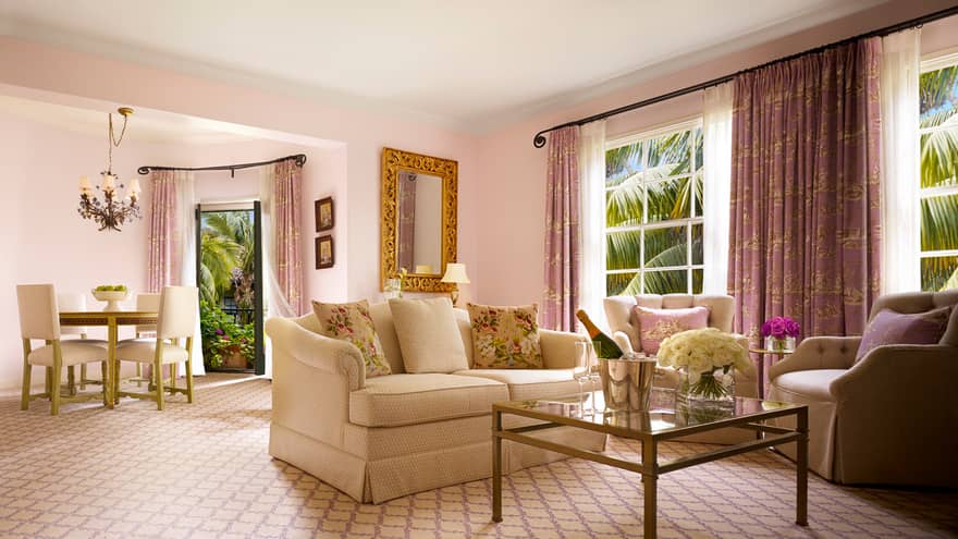 Honeymoon Suite white loveseat, armchairs around glass coffee table, bucket with wine