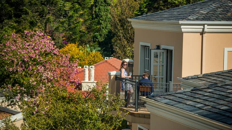 Looking down over corner of hotel roof at man and woman sipping cocktails on sunny balcony
