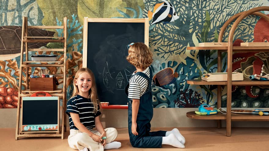 Two children play in play area with chalkboard