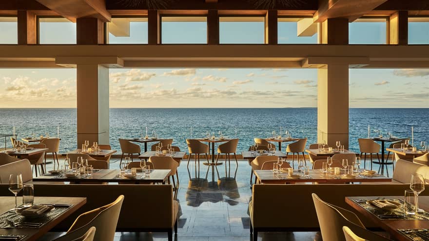 Elegant Coba open-air restaurant with dining tables and chairs, gleaming floors over open ocean