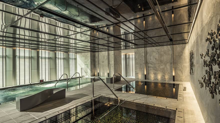 Two indoor pools, vitality pool on tile deck surrounded by marble walls, windows