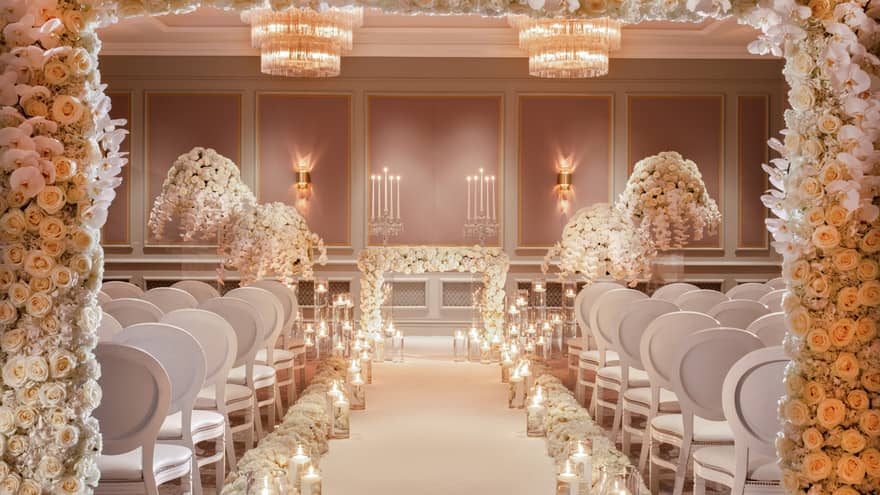 Wedding ceremony set up in event room, doorway filled with roses and glowing candles down aisle