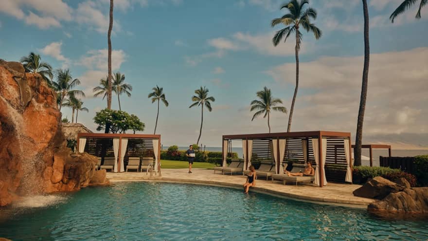 Waterfall swimming pool with cabanas and palm trees