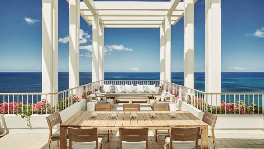 Penthouse Suite large patio dining table, seating area under white pergola, blue sky