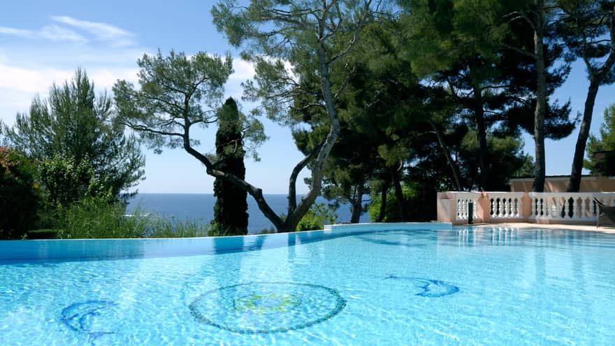 Blue outdoor swimming pool, trees, sea views