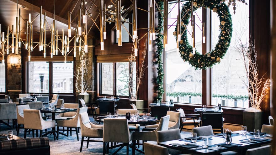 The inside of a restaurant with holiday decorations and snow visible through a large window.