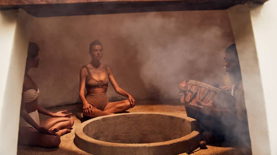 Three people sitting in a heated room with steam.