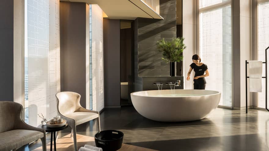 Spa staff draws bath in freestanding tub in large room
