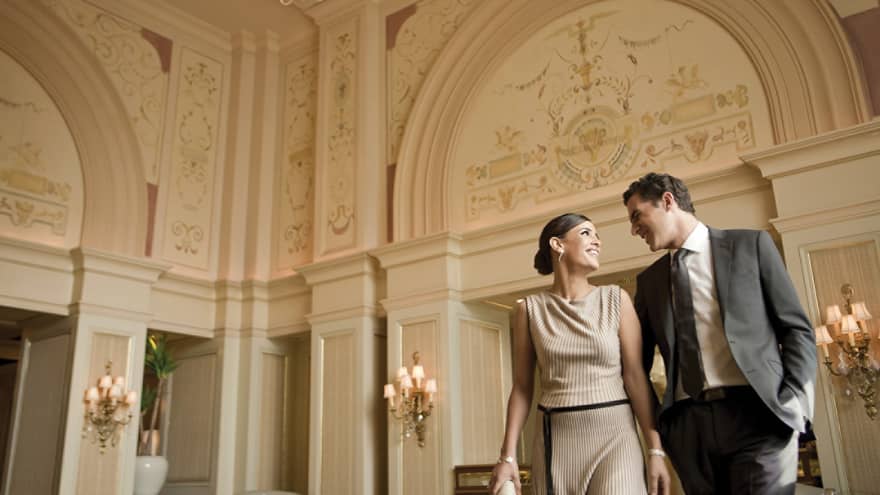 Smiling woman and man in business attire walk through hotel lobby
