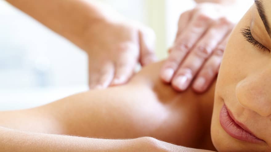 Close-up of woman's face with eyes closed, bare shoulder as she gets a Balinese massage