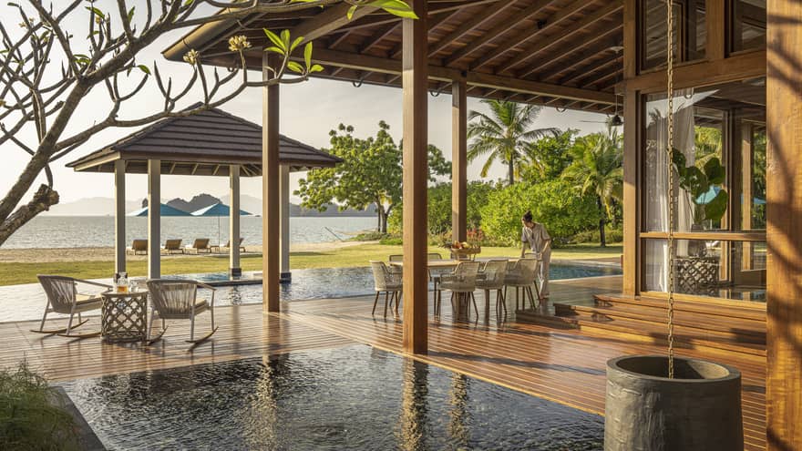 Private pool terrace and wooden deck under pergola, looking out to green lawn and Langkawi beach