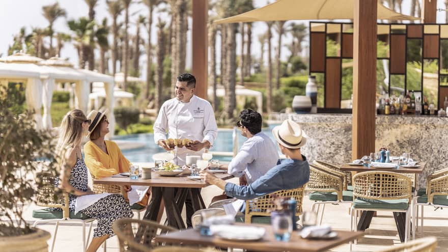 Chef greets table of four guests on outdoor terrace at Luna