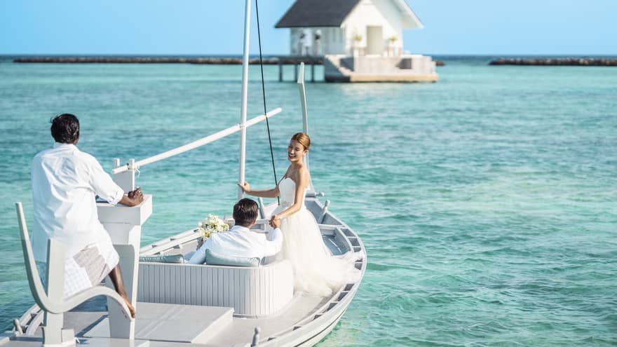 Bride and groom head toward their overwater wedding venue in traditional Maldivian boat
