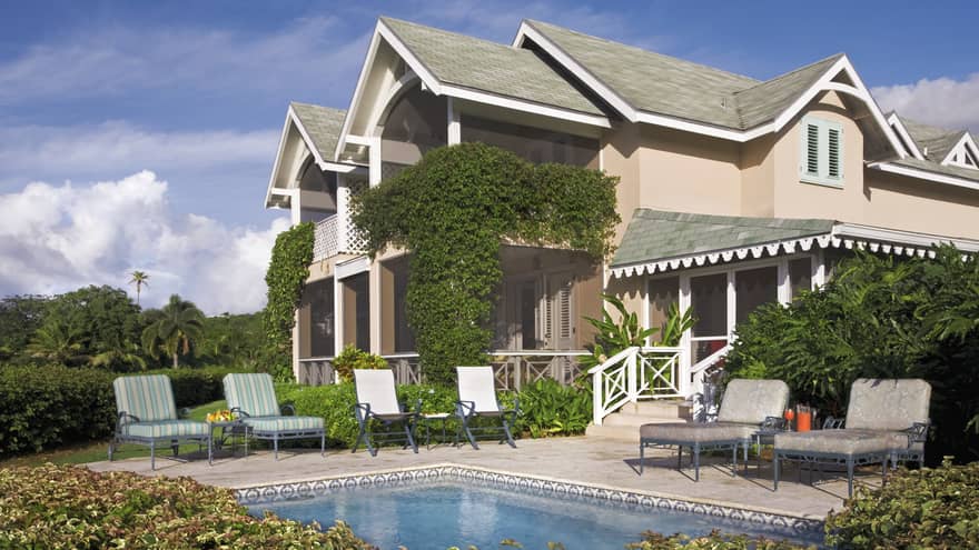 Palm Grove Residence exterior behind private pool, lounge chairs on deck