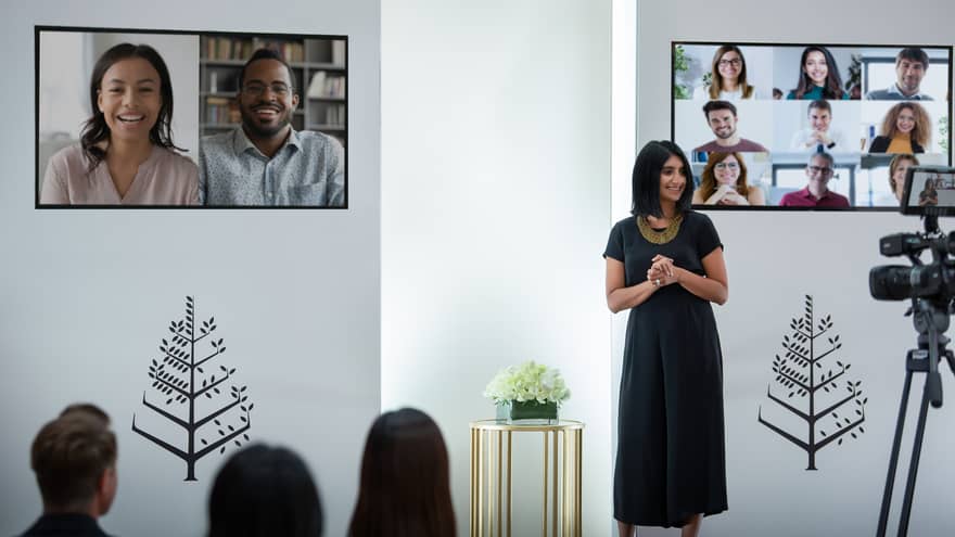 Several people host a virtual meeting in a room with the Four Seasons logo.