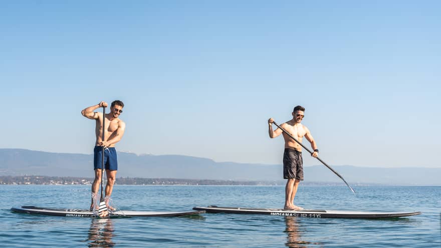 Two men stand-up paddleboarding on Lake Geneva