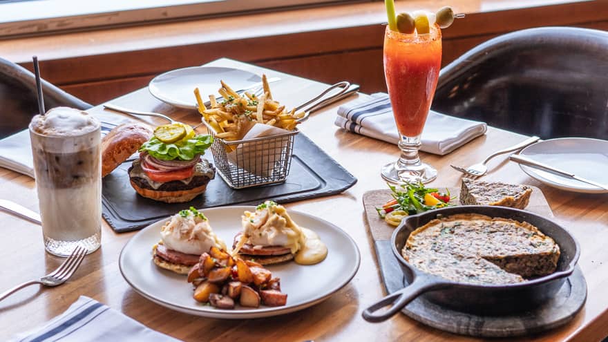 An assortment of food, including eggs Benedict, a burger and fries and quiche.