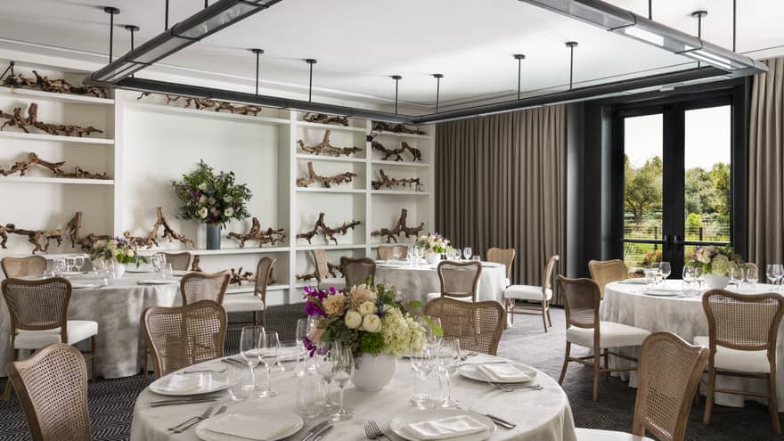 Event room with banquet tables, wall of built-in shelves, large square lighting fixture