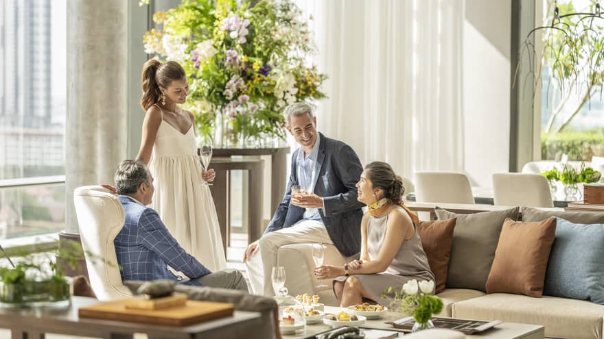 A group of people mingle in luxury living room with lots of natural light