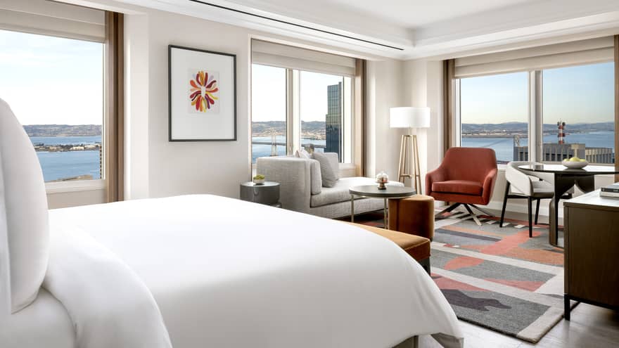 King bed, chaise, and small dining table facing panoramic window