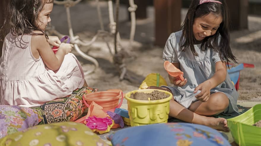 Two young girls play in the sand at Lutong Kids Club
