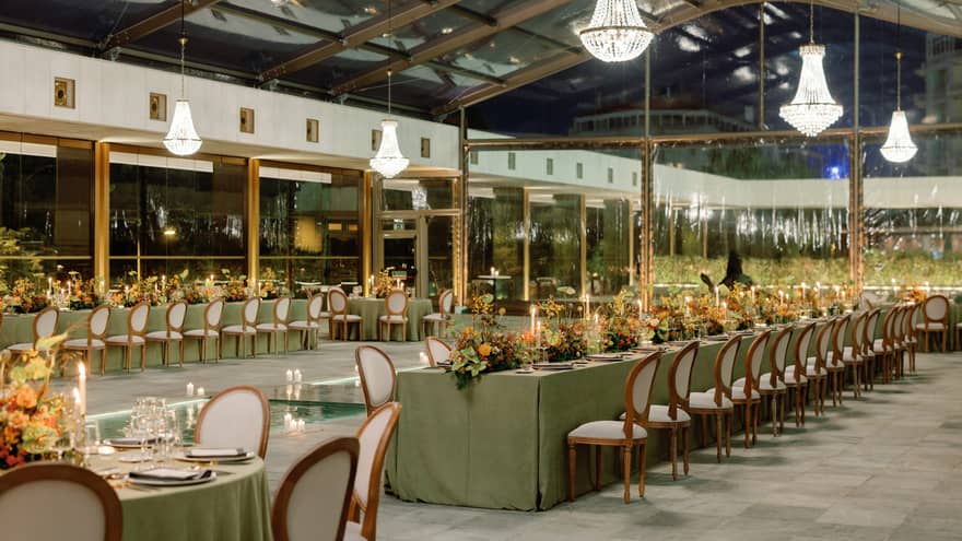 Rows of lavish wedding tables under crystal chandeliers at night