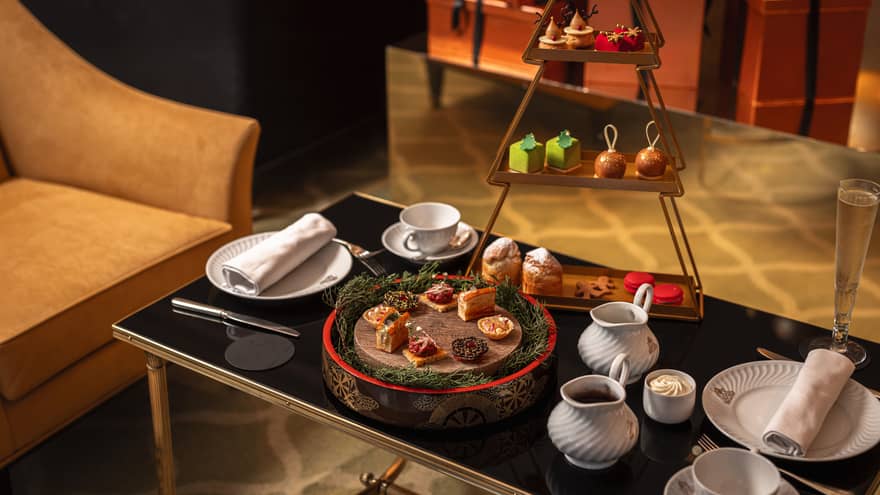 Festive afternoon tea setup on black glass coffee table
