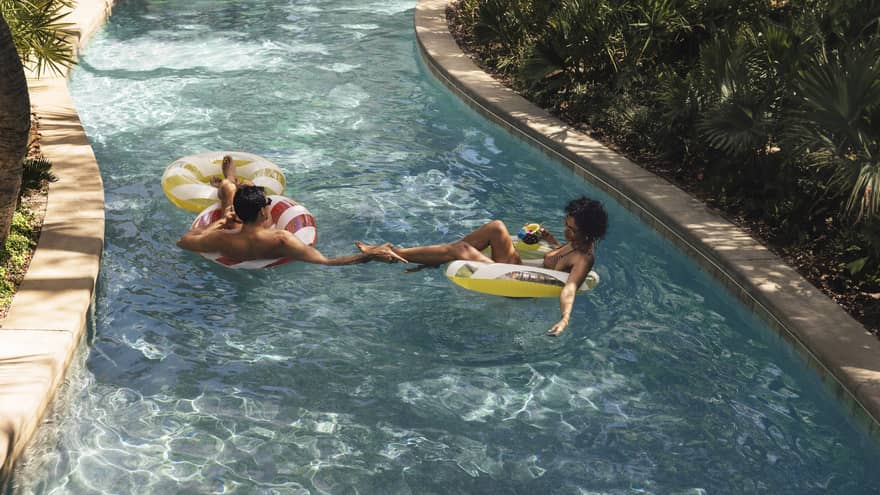 Man and woman float in a lazy river at luxury resort