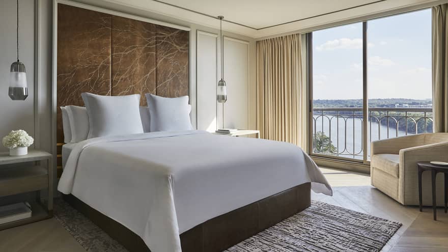 Governor's Suite hotel room bed under large leather headboard with branch pattern, large windows