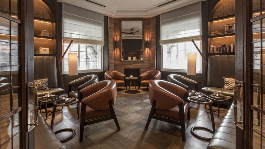 A warmly lit, sophisticated lounge with leather chairs and banquettes arranged in groups around small cocktail tables.