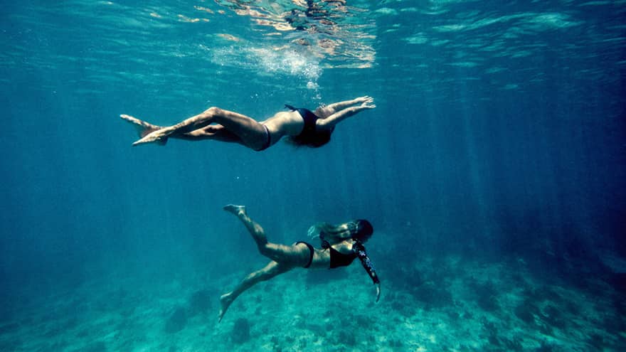 Underwater view of two women swimming in ocean