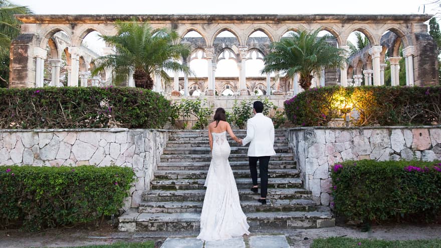 Back of bride and groom walking up stone steps to pillars, Beach Deck