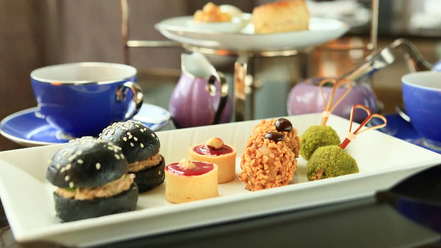 Small appetizers, sweets on white tray near tea service 