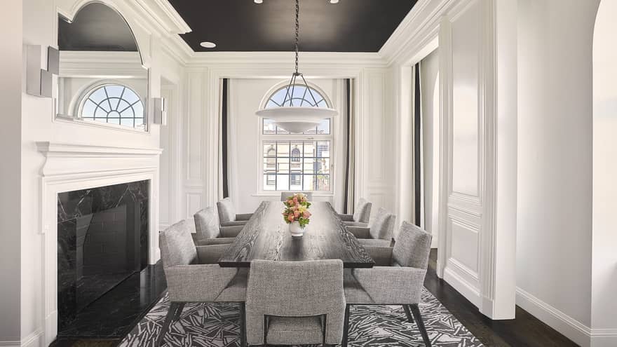 Dining room with fireplace, arched window, and dark wood table with eight grey cushioned chairs