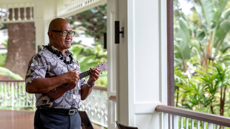 K?naka Maoli elder plays the ukelele on the second-story wraparound porch of the Resort