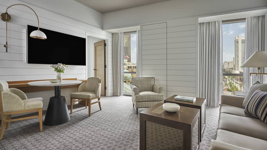 Suite with white panel walls, coffee table, sofa, two chairs, small table and television