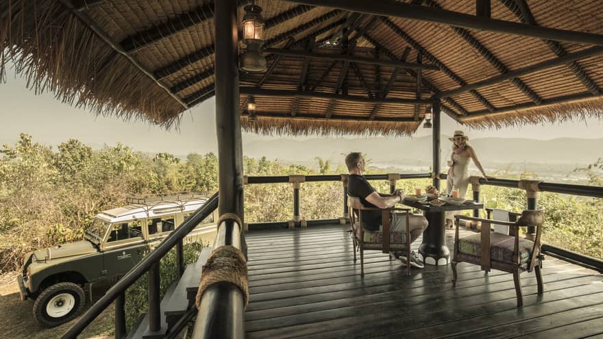 Couple enjoys Camp Peak Breakfast on platform patio near utility vehicle
