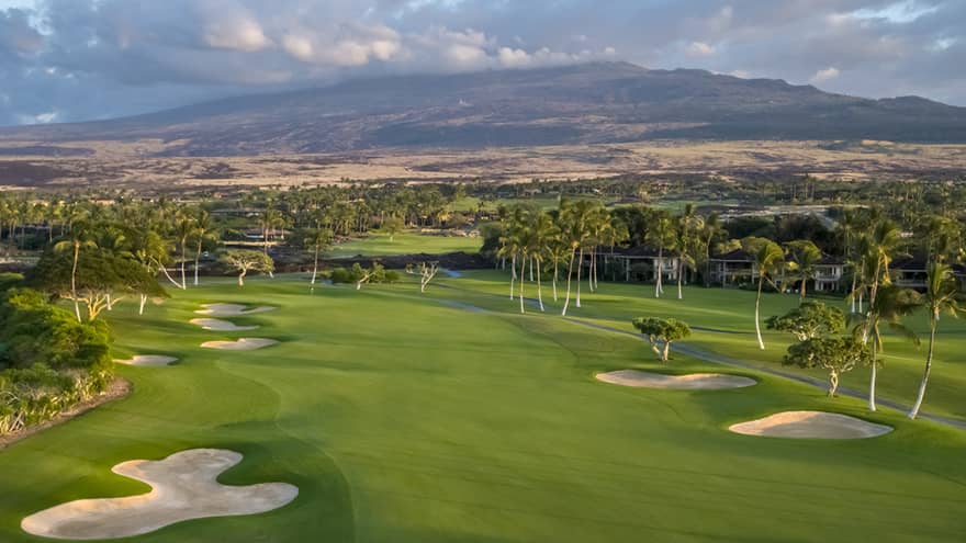 A golf course with greens, sand pits and trees.