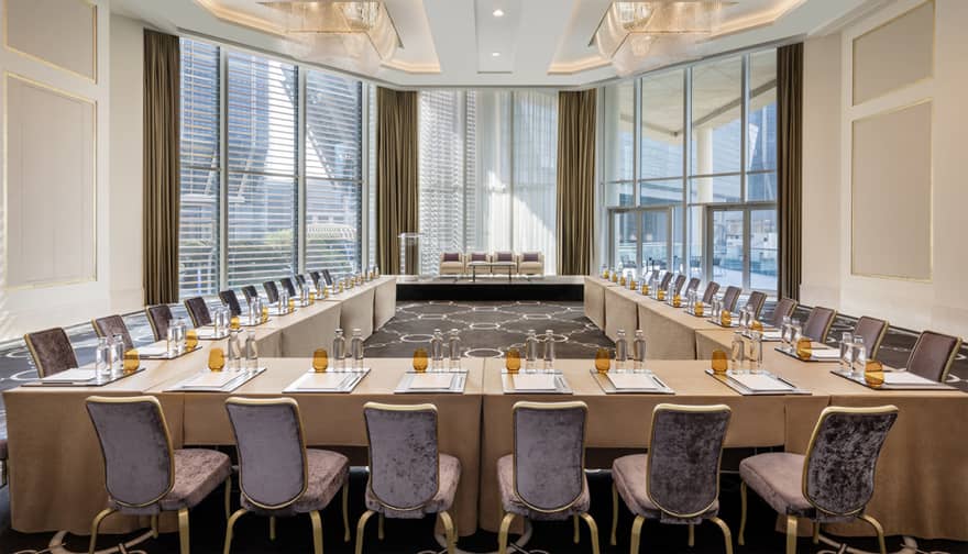 Meeting room with rectangular tables set up in a u-shape facing floor-to-ceiling windows