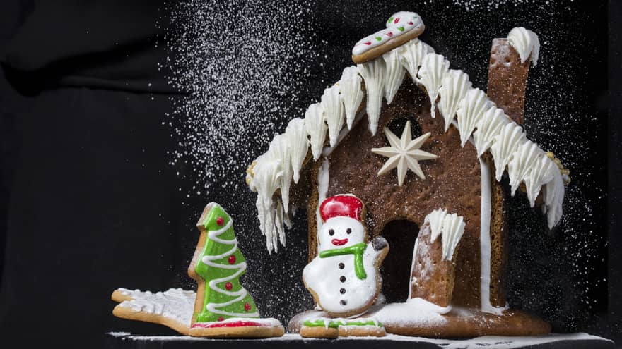 Gingerbread house being dusted with powdered sugar that looks like snow,Gingerbread house being dusted with powdered sugar that looks like snow