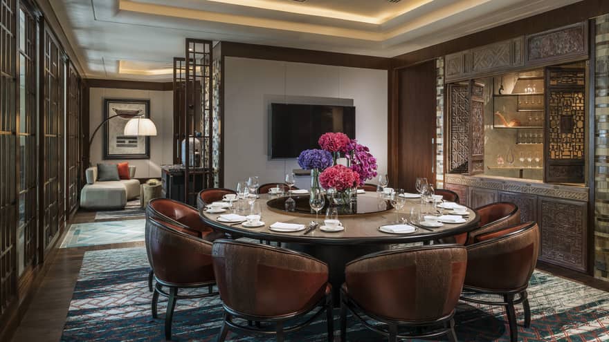 Leather bucket chairs around private meeting dining table, TV on wall
