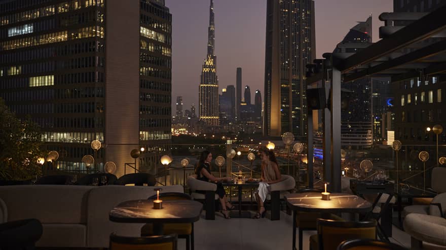 Nightime view of rooftop lounge with Dubai skyline in background
