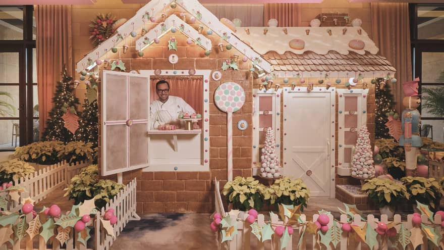 Chef stands inside of a life-size gingerbread house