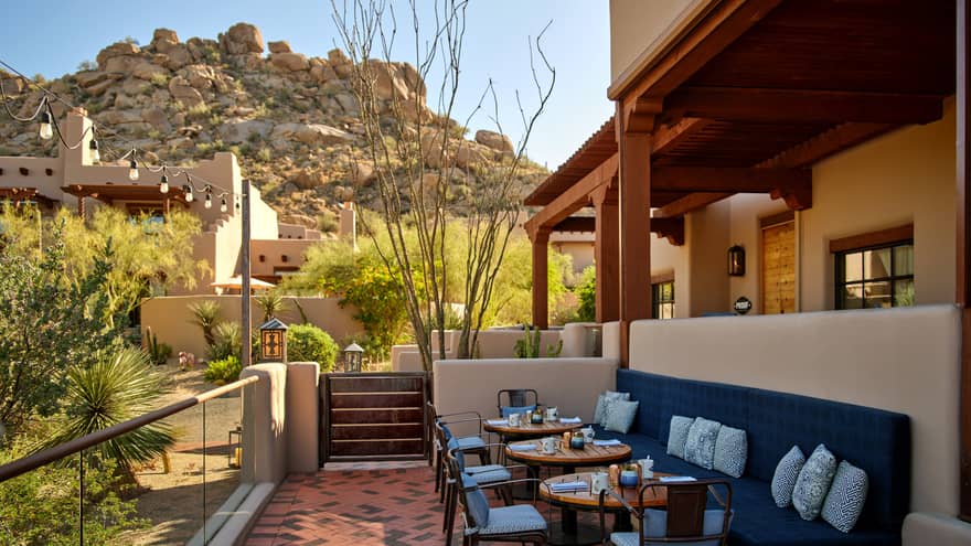 Outdoor terrace with booth seating and chairs and a view of the mountains.