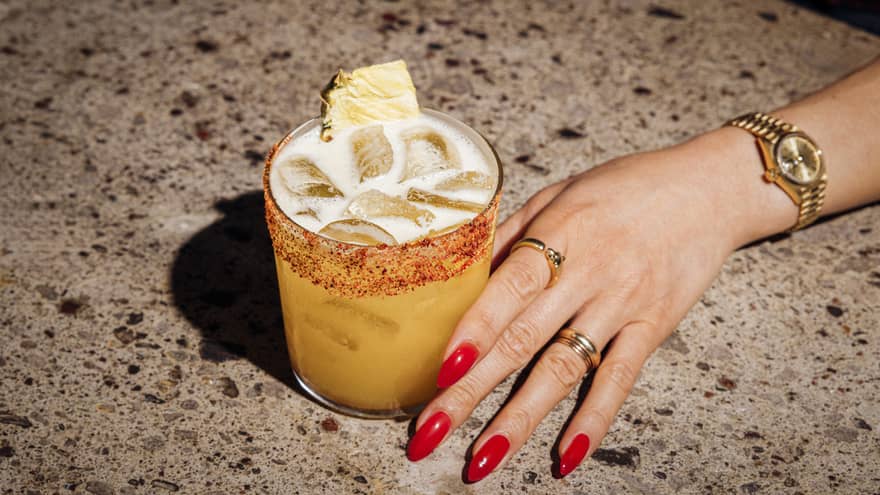 Pisco cocktail and woman's hand with red nail polish