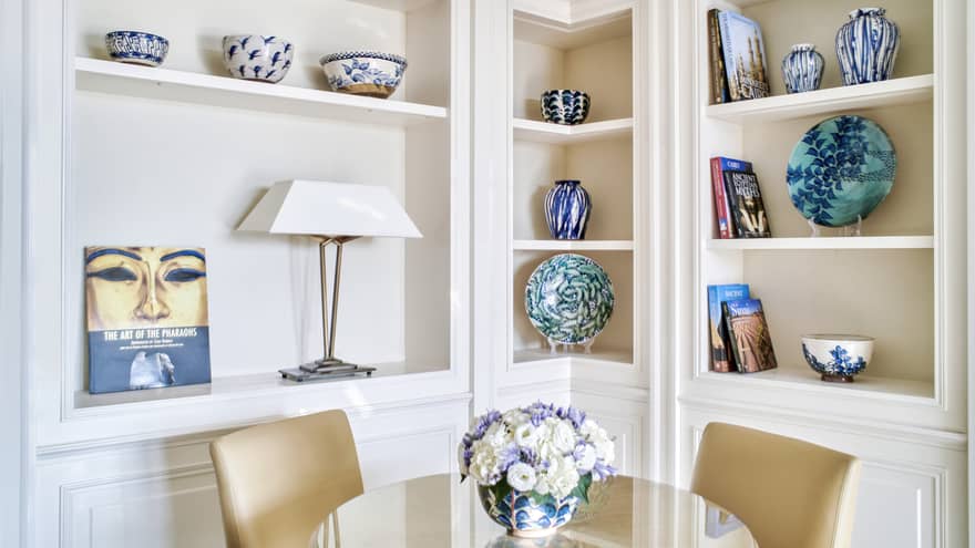 Premium Executive Suite dining area with two-seater round glass table, built-in shelves lined with colourful artefacts