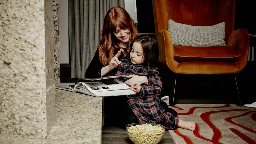 Woman and kid reading a book and eating popcorn