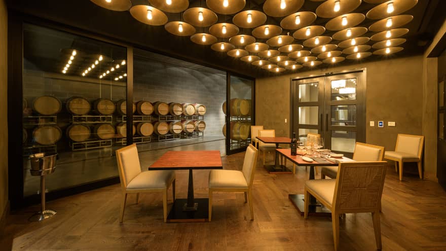 Three small rectangular tables set up in a wine cellar